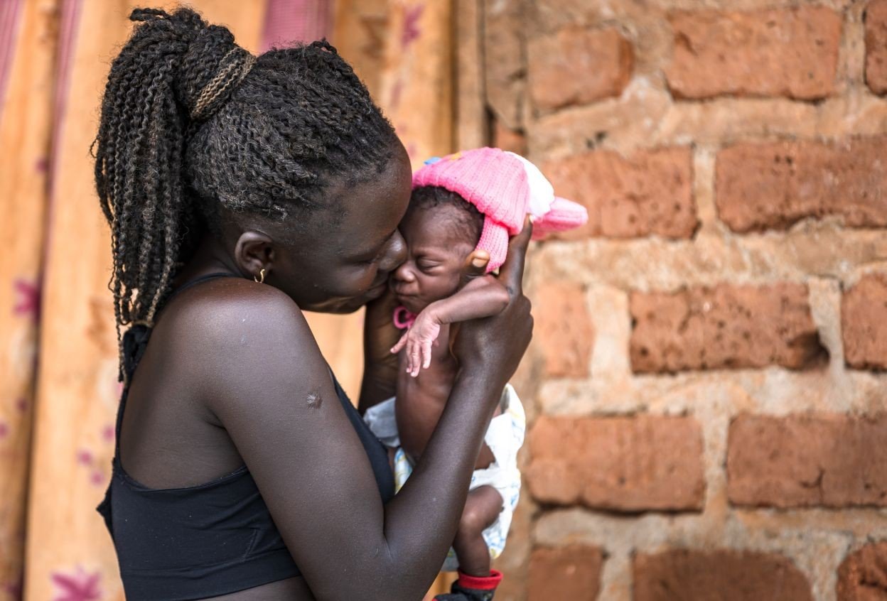 Community health worker with a mother and child in a Ugandan village